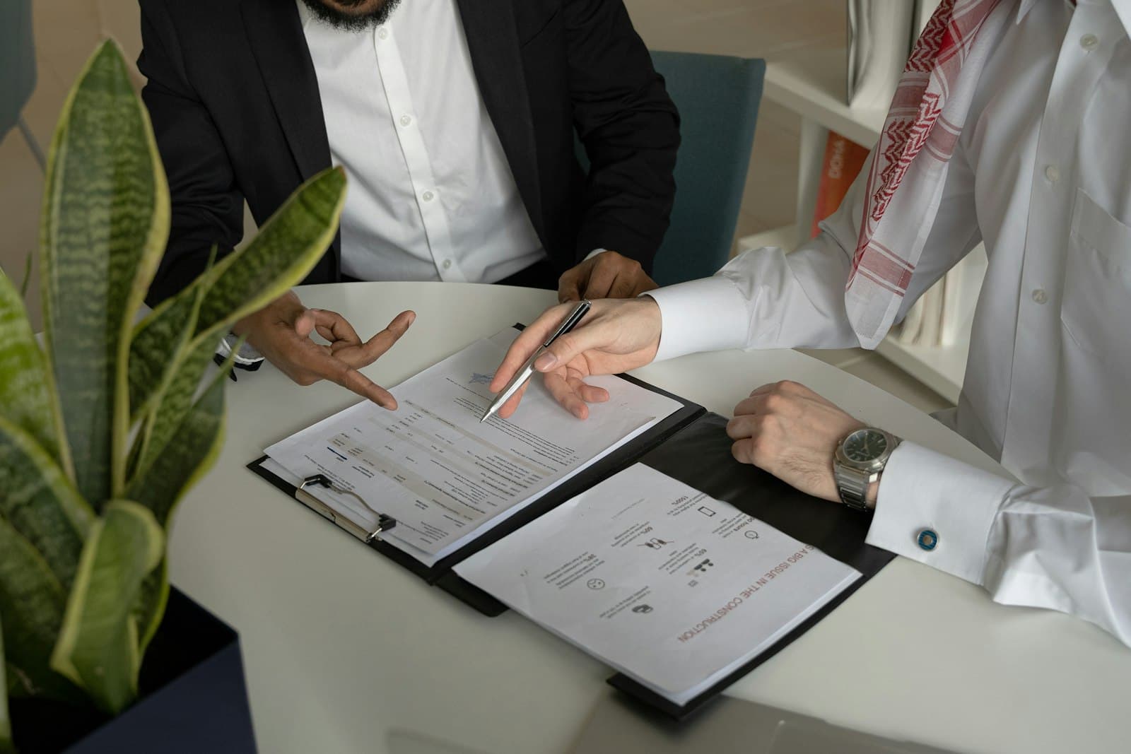 Two people comparing loan program documents side by side across a desk