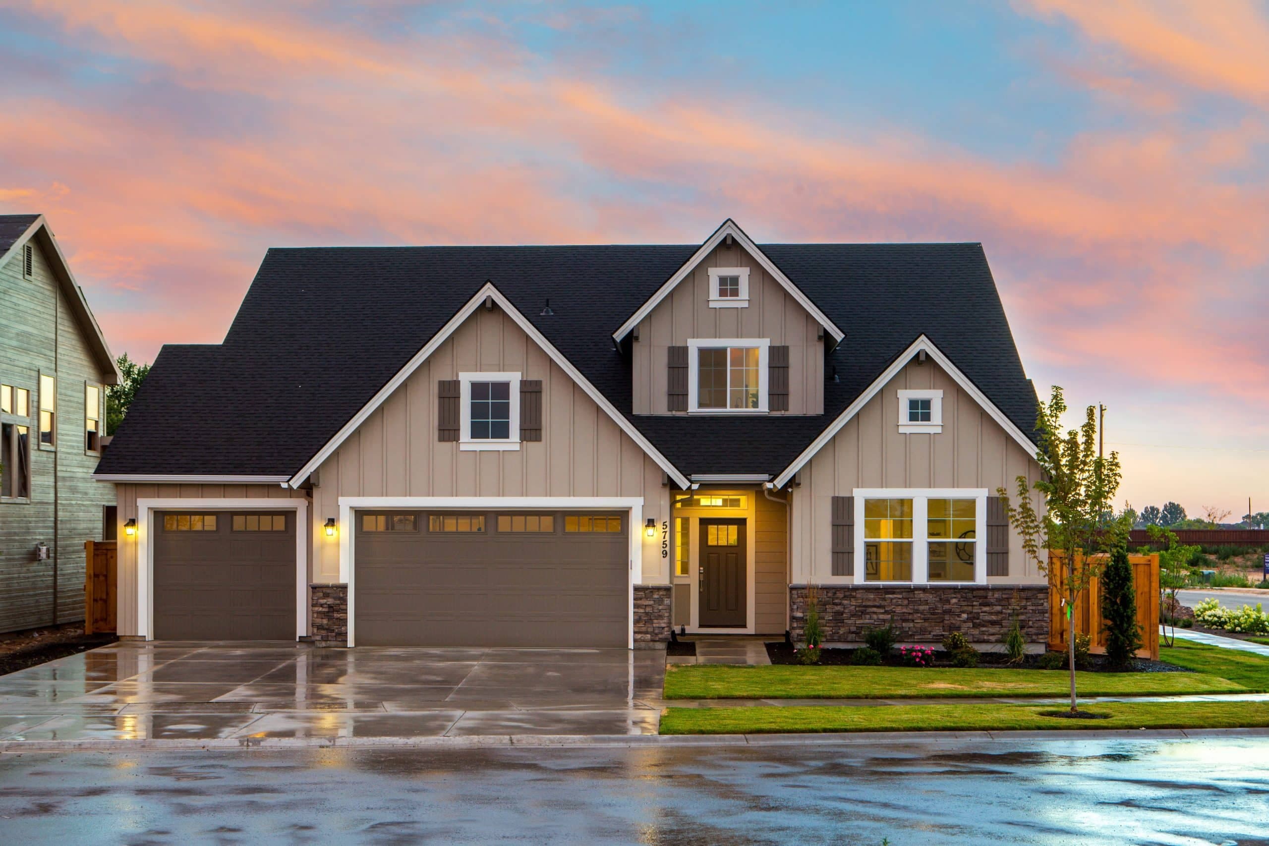 A newly built American single-family home at dusk, lights on inside