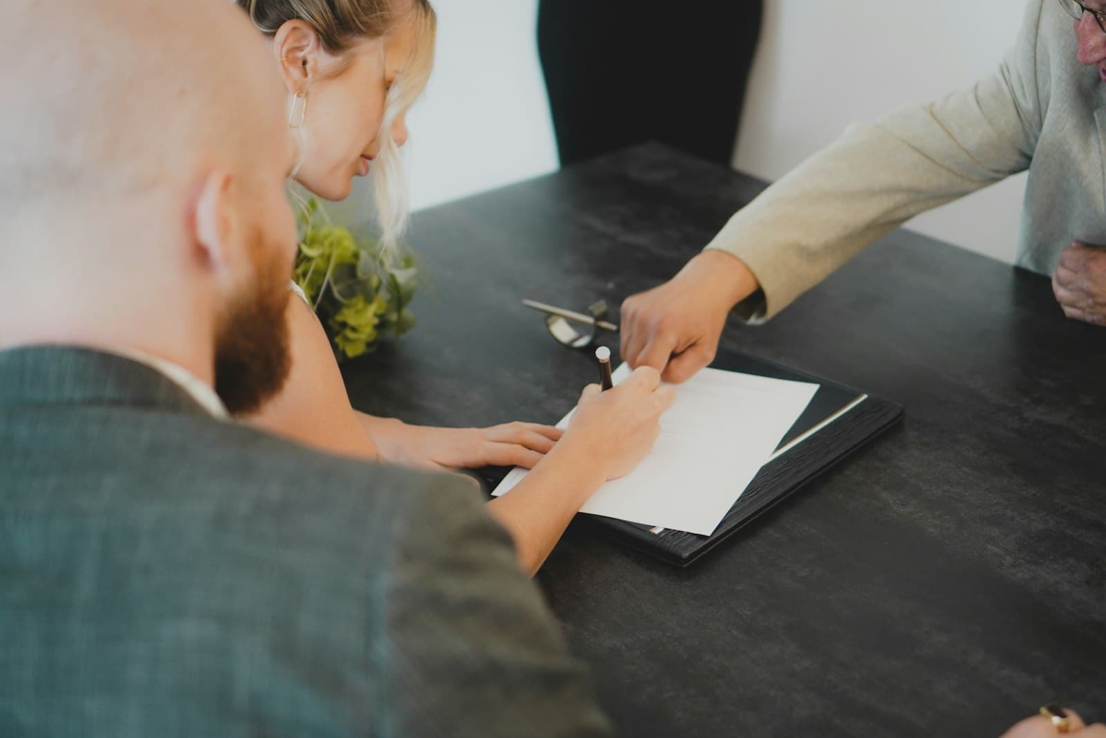A couple signing paperwork while an adviser points to the page