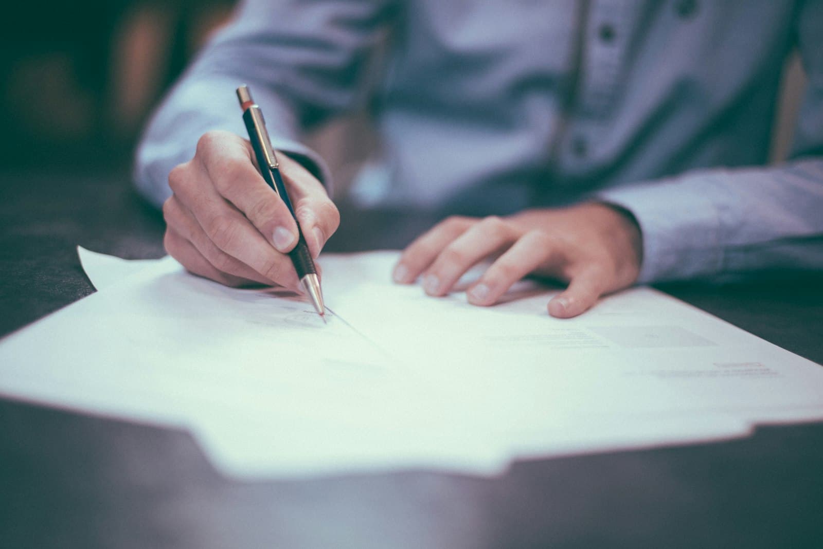 A close-up of a hand signing a document with a pen