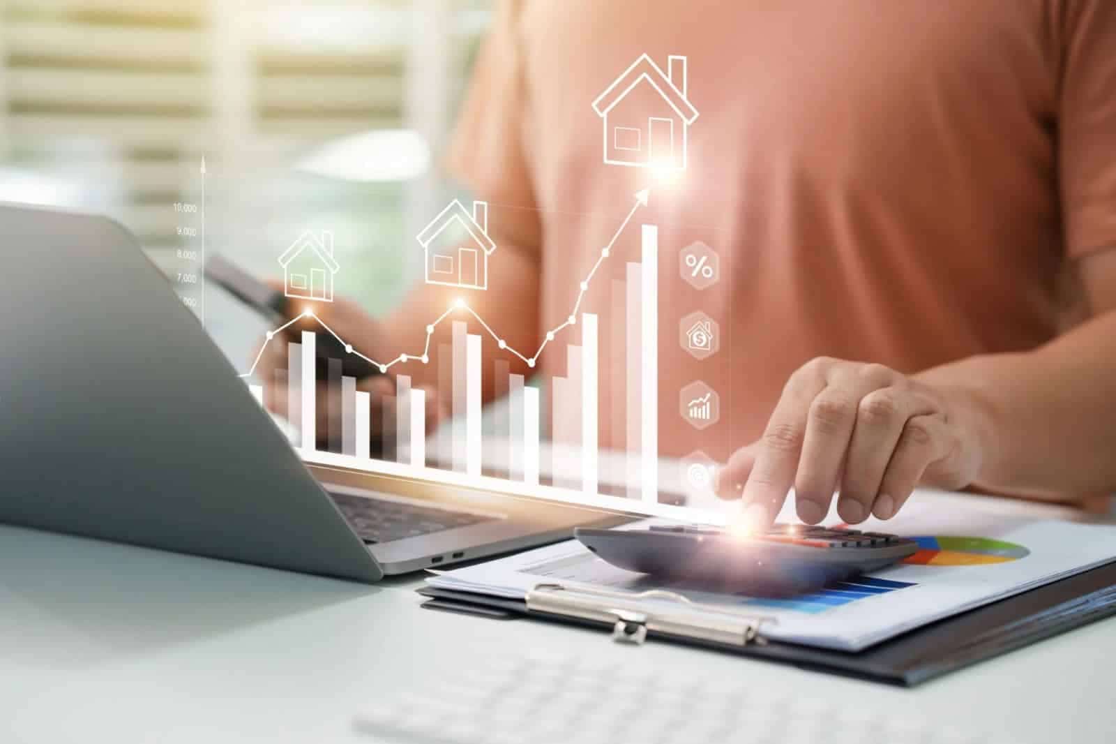 Person using a calculator and laptop to review rental property financial data with charts and real estate investment growth graphics.