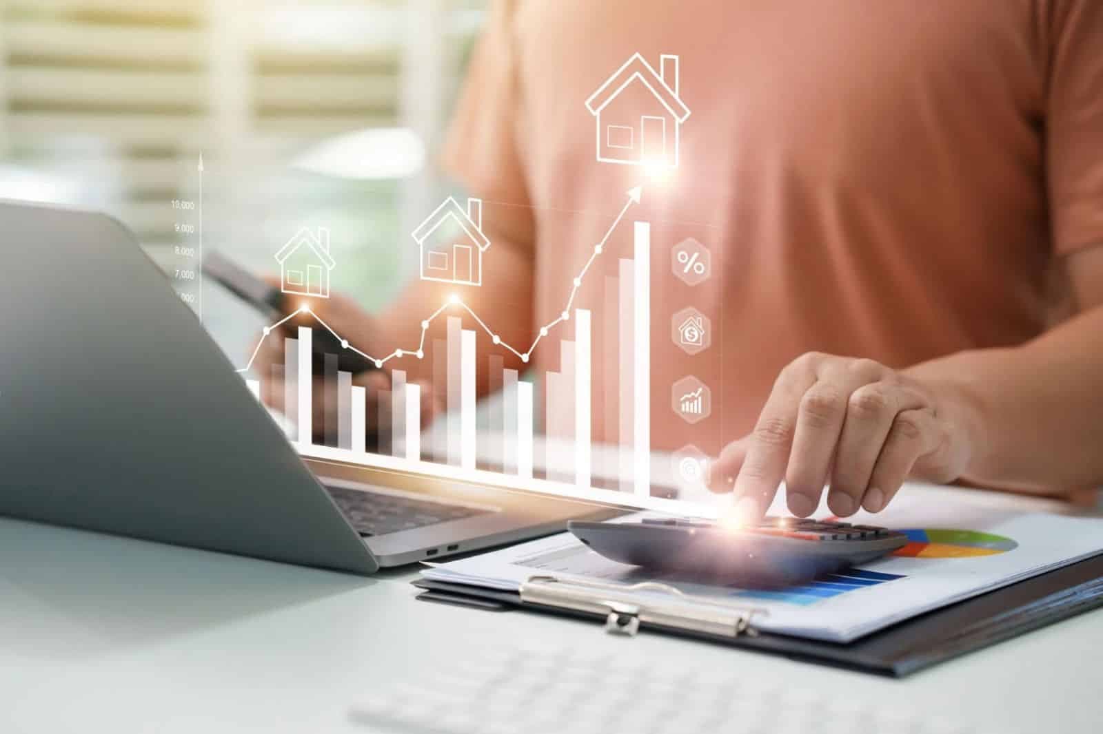 Person using a calculator and laptop to review rental property financial data with charts and real estate investment growth graphics.